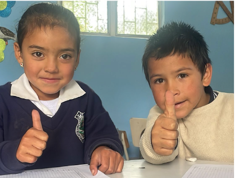 Niños en aula haciendo gesto de aprobación